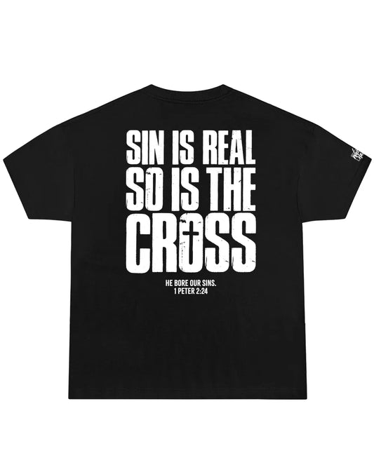 Black oversized Christian streetwear shirt featuring bold “Sin Is Real So Is The Cross” typography with 1 Peter 2:24 scripture reference.