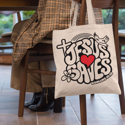 Natural Canvas Tote bag with 'Jesus Saves' with a Cross and Dove that represents the Holy Spirit design held by a person sitting on a chair.