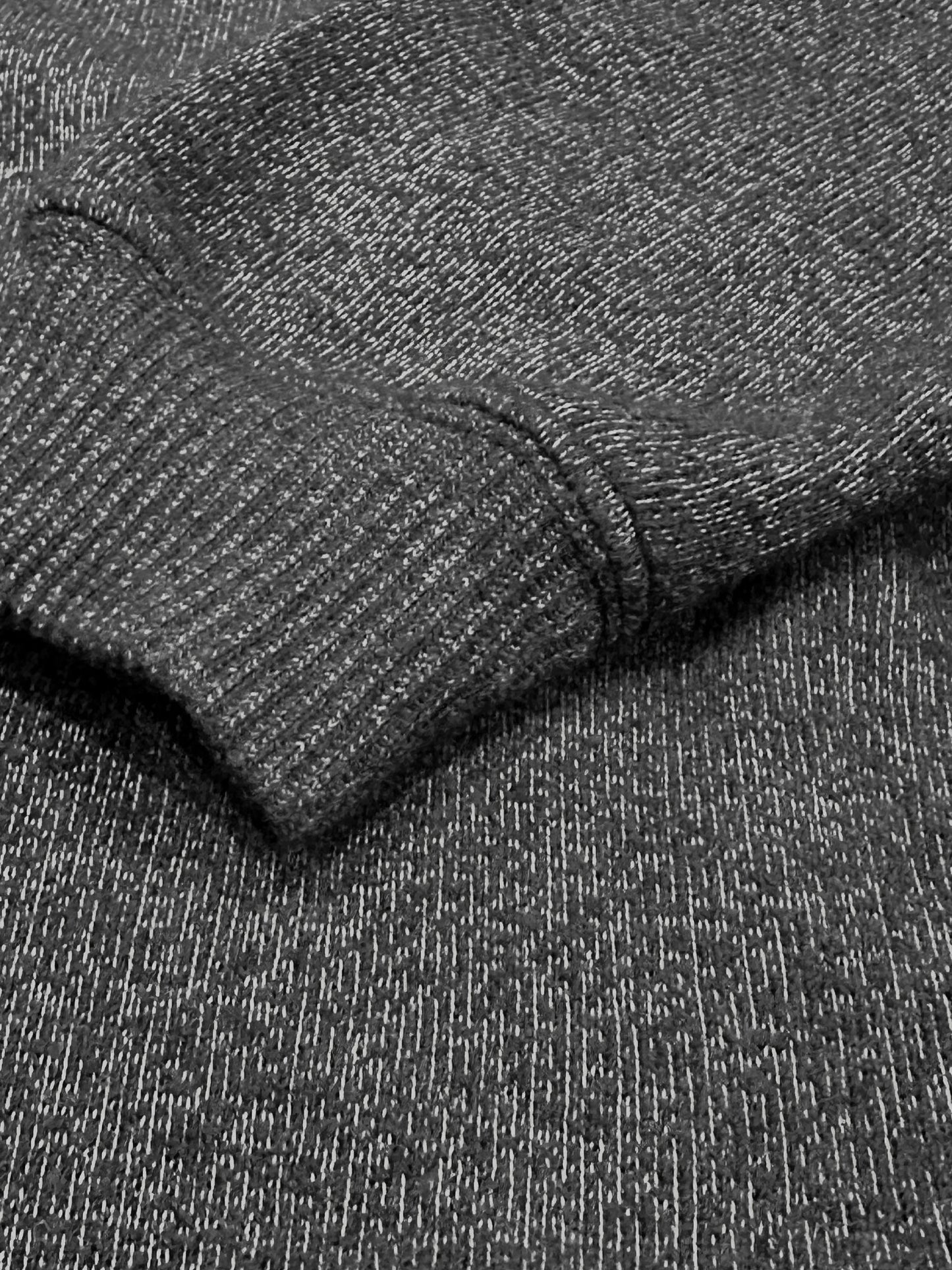 Close-up of dark grey ultra soft plush knit textured fabric with a folded pattern with ribbed cuffs